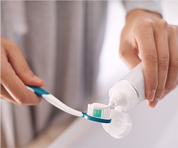 Applying toothpaste to a toothbrush.