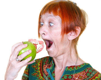 Woman biting a green apple with surprise expression.