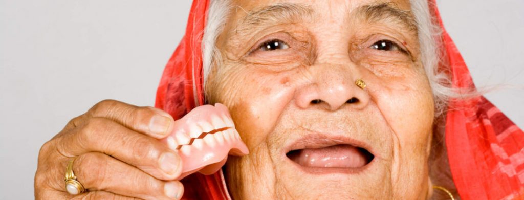 happy old woman holding denture